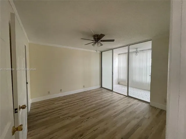 an empty room with wooden floor and a ceiling fan