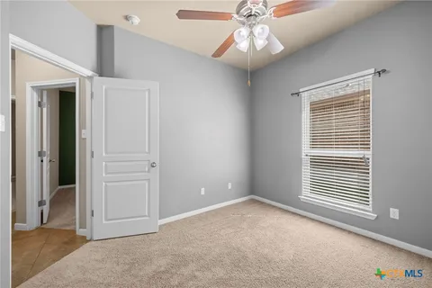 en empty room with windows and ceiling fan
