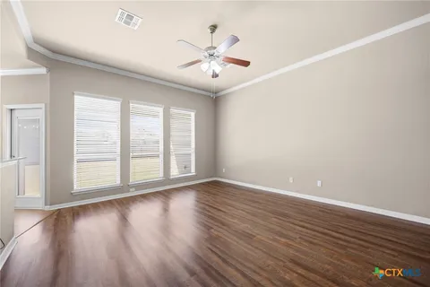 an empty room with wooden floor chandelier fan and windows