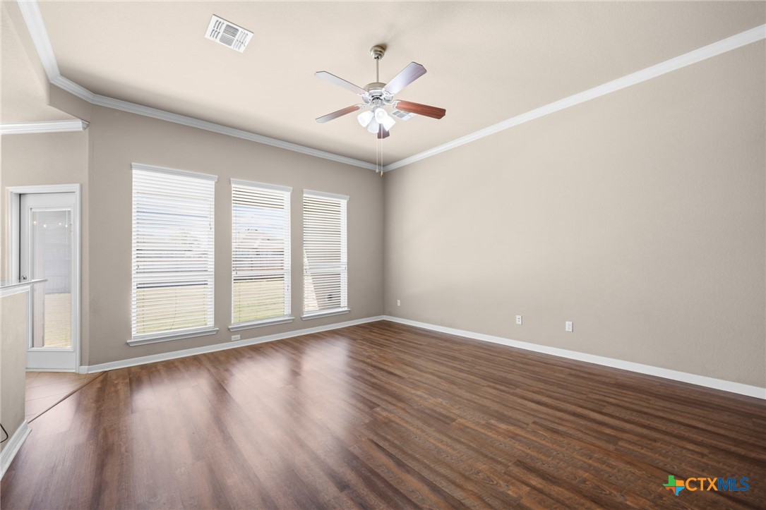 517 Coventry Drive Temple, TX 76502 - Photo 5 of 34 an empty room with wooden floor chandelier fan and windows