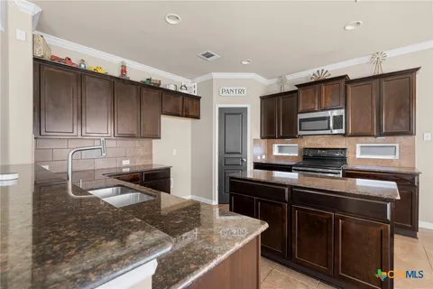 a kitchen with kitchen island granite countertop a stove sink and microwave