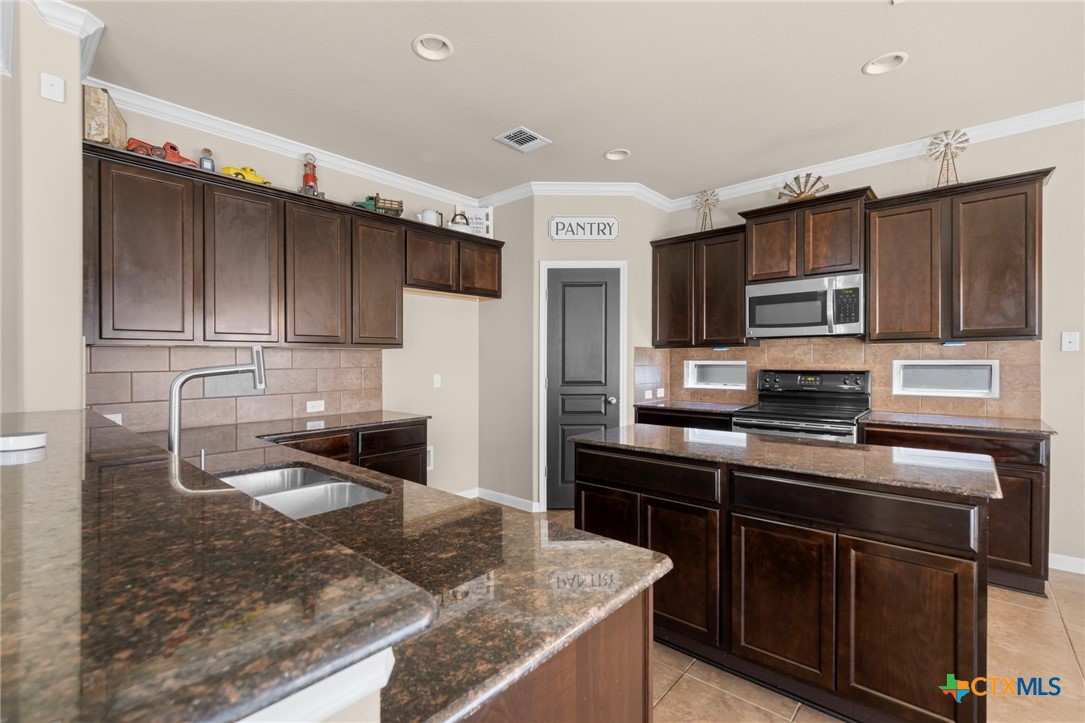517 Coventry Drive Temple, TX 76502 - Photo 10 of 34 a kitchen with kitchen island granite countertop a stove sink and microwave