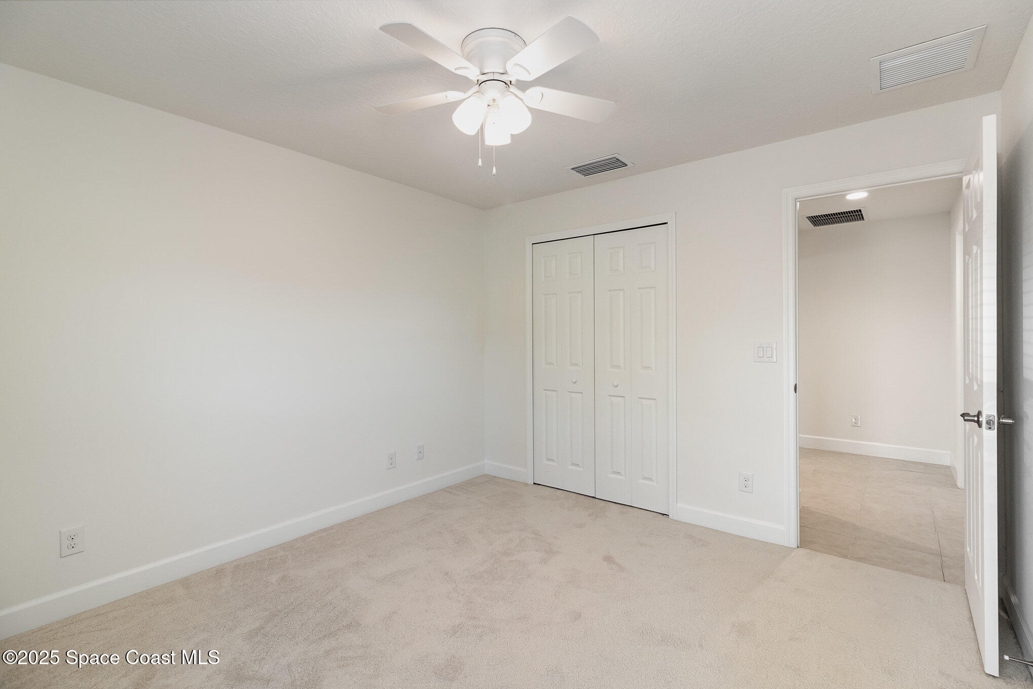 691 Belvedere Road Northwest Palm Bay, FL 32907 - Photo 14 of 26 an empty room with a chandelier fan and windows