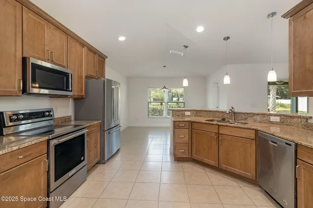 a large kitchen with stainless steel appliances granite countertop a large stove top oven a sink dishwasher a dining table and chairs with wooden floor