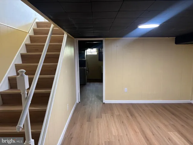 a view of an empty room with wooden floor and stairs