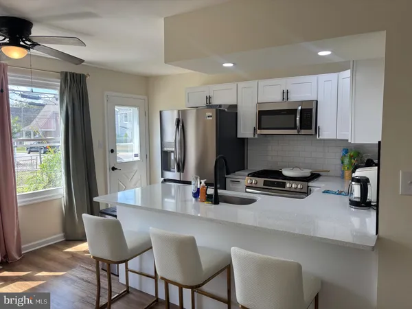 a kitchen with stainless steel appliances a microwave sink refrigerator dining table and chairs