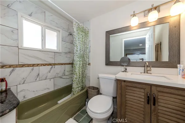 a bathroom with a granite countertop toilet sink and mirror