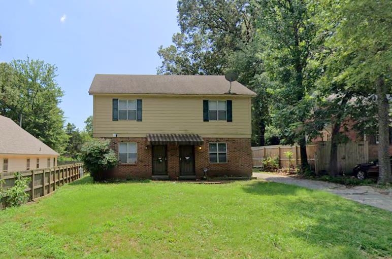Back of house featuring brick siding, a fenced backyard, and a yard