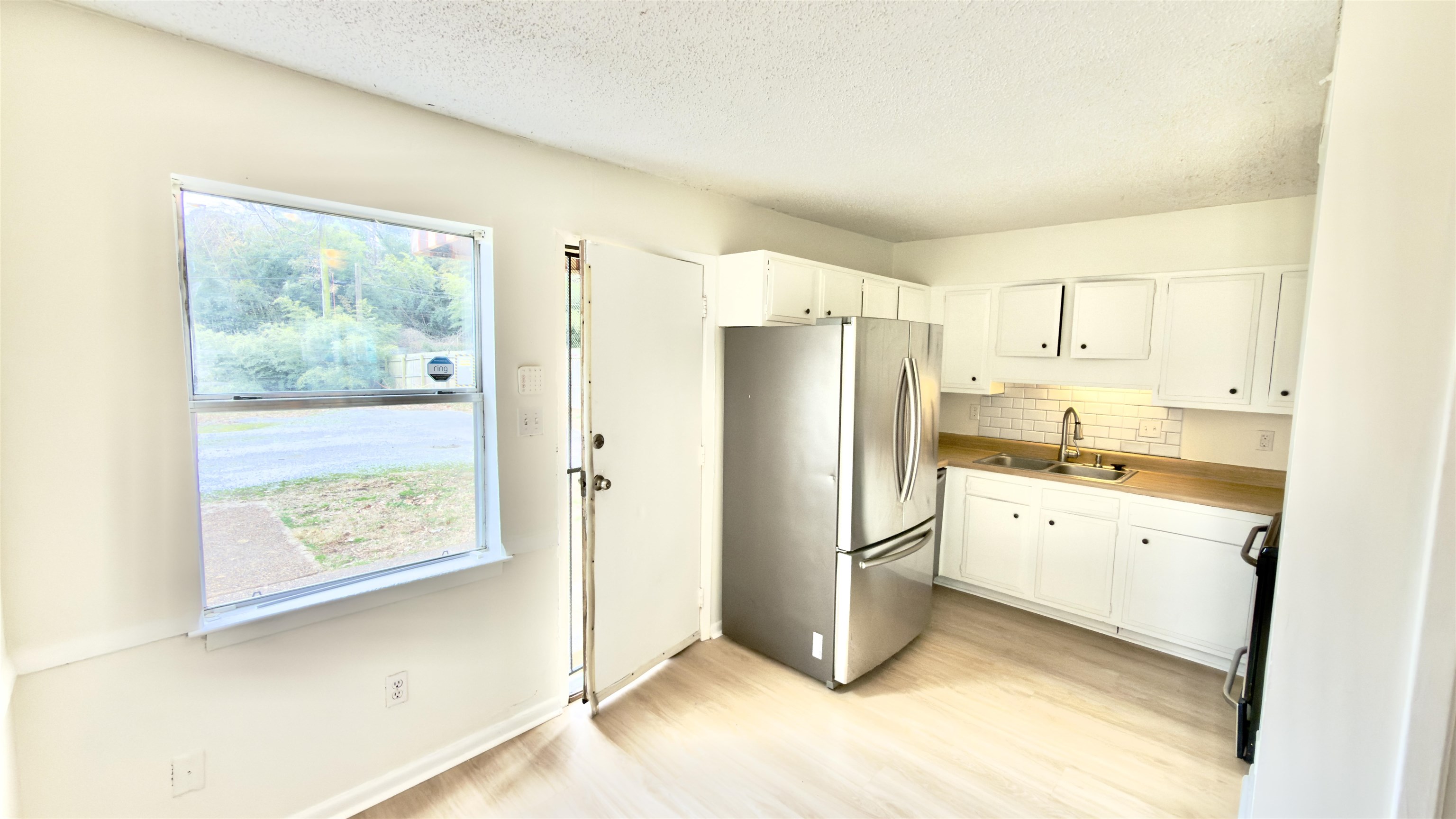 3799 Carnes Avenue Memphis, TN 38111 - Photo 10 of 16 Kitchen featuring freestanding refrigerator, white cabinets, backsplash, light countertops, and a textured ceiling