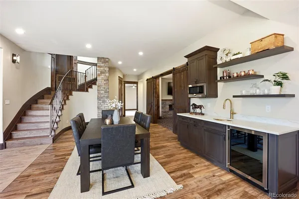 a dining hall with stainless steel appliances kitchen island granite countertop a dining table and chairs with wooden floor