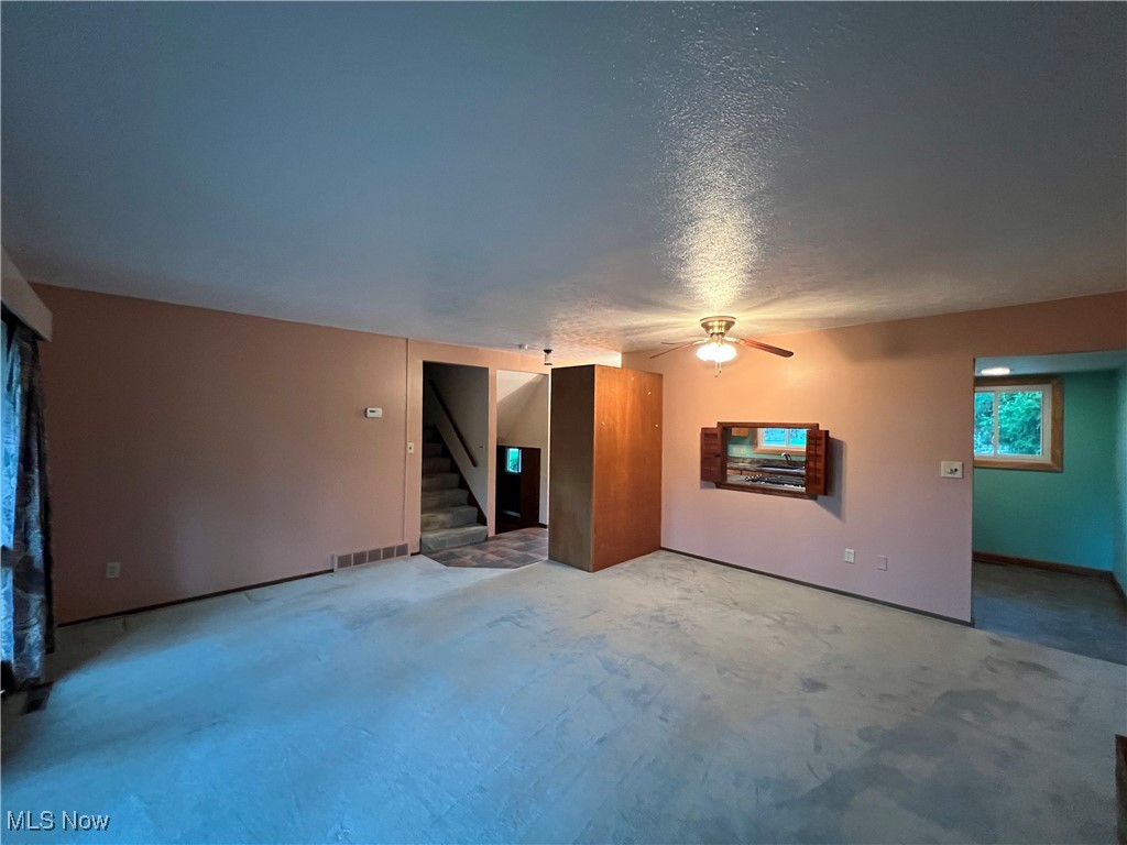 218 Nobottom Road Berea, OH 44017 - Photo 5 of 14 Unfurnished living room featuring a textured ceiling, ceiling fan, and stairway