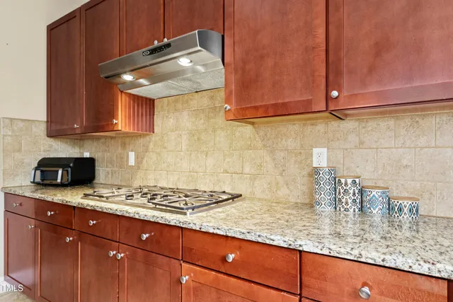 a kitchen with stainless steel appliances granite countertop a refrigerator a sink dishwasher a stove with wooden cabinets and floor