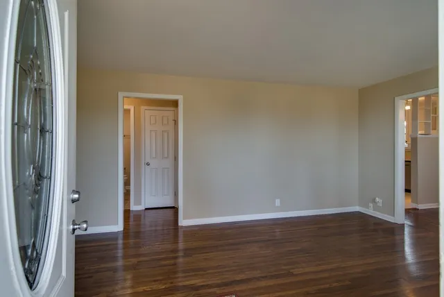 a view of an empty room with wooden floor and a window