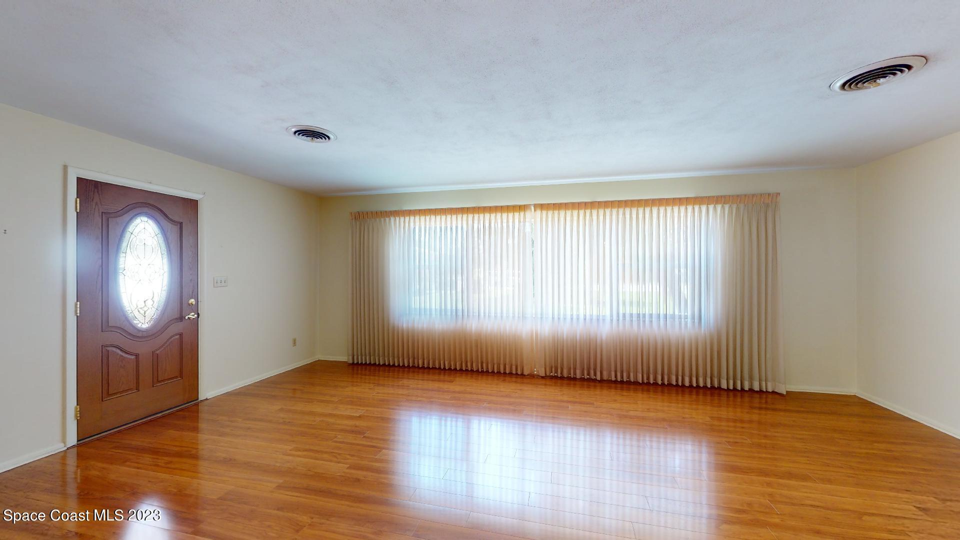 204 South Riverside Drive Indialantic, FL 32903 - Photo 6 of 24 an empty room with wooden floor and windows