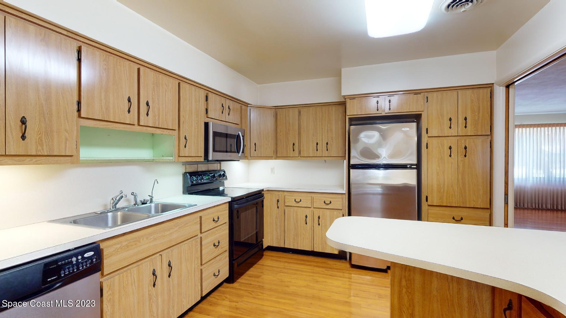 204 South Riverside Drive Indialantic, FL 32903 - Photo 8 of 24 a kitchen with stainless steel appliances a refrigerator sink and cabinets