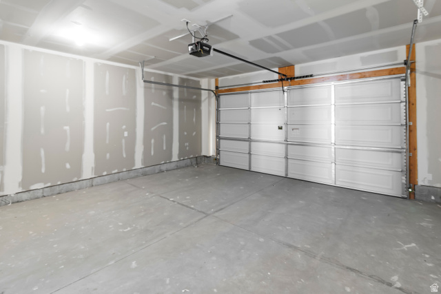2995 South 265th Street West, Unit 752 Logan, UT 84321 - Photo 21 of 21 Spacious garage featuring a sectional overhead door, exposed wood framing, concrete flooring, and ceiling-mounted garage door opener