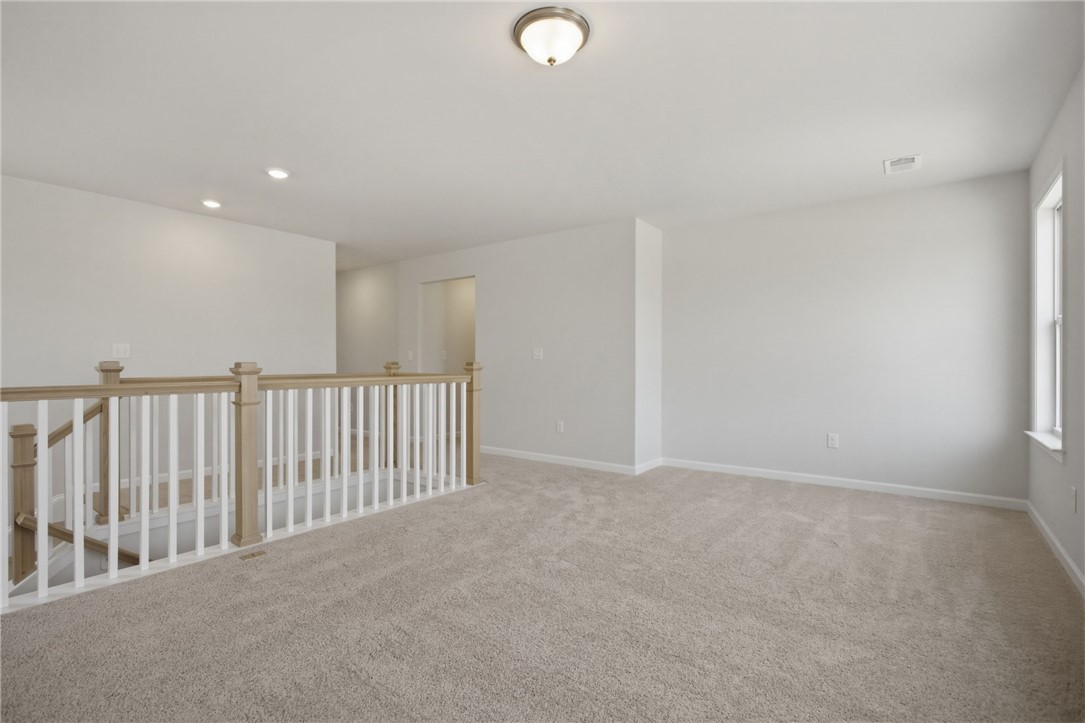 557 Hydrangea Street, Unit LOT 46 Seneca, SC 29678 - Photo 22 of 37 A spacious upper-level bonus room awaits customization, featuring soft carpeting and natural light from a well-placed window.