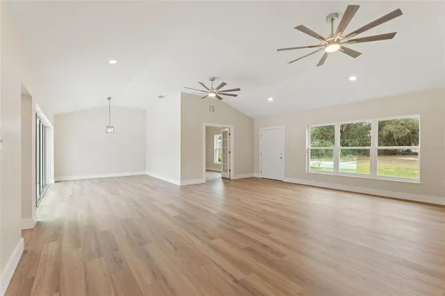 a view of an empty room with a window and wooden floor