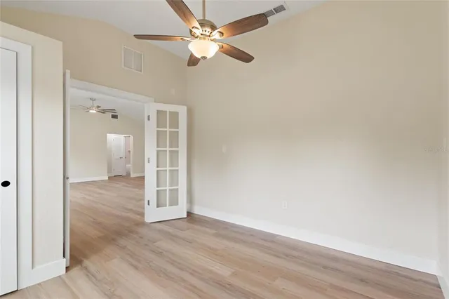 an empty room with wooden floor and fan