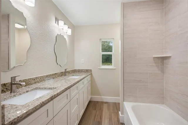 a bathroom with a granite countertop sink a mirror and a bathtub