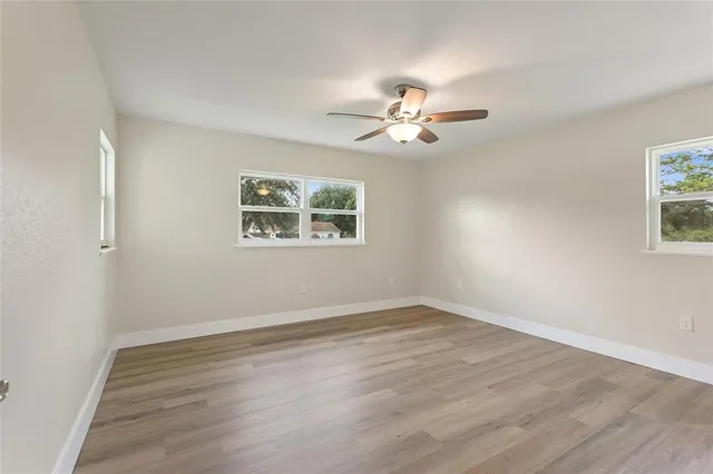 a view of an empty room with a window and a chandelier fan