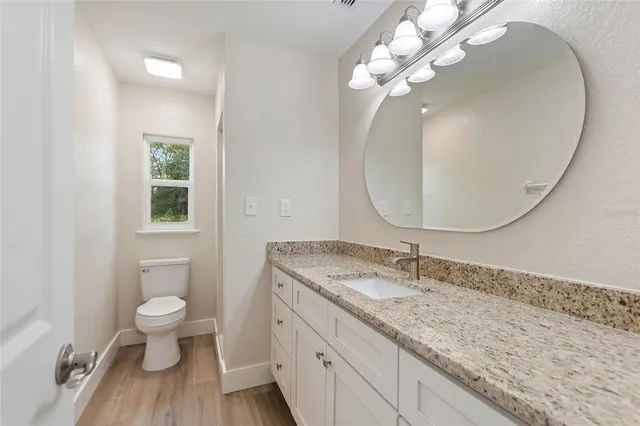 a bathroom with a granite countertop sink a toilet and a mirror