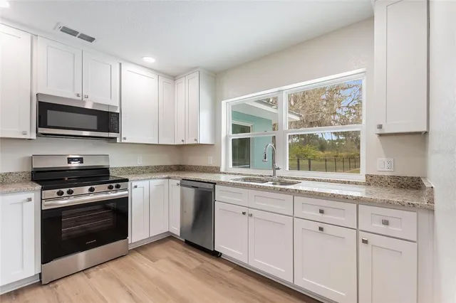 a kitchen with granite countertop white cabinets a sink and a window