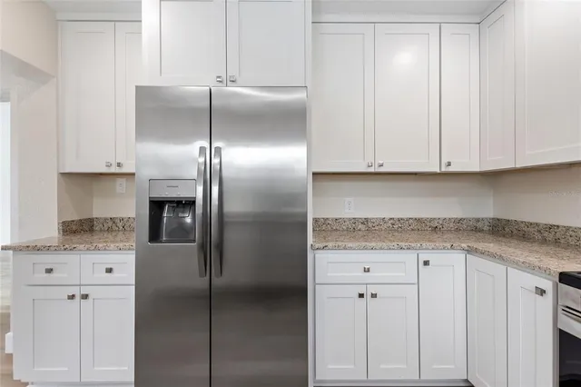 a kitchen with stainless steel appliances granite countertop a refrigerator a stove and white cabinets