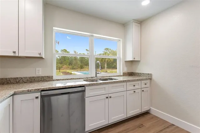 a kitchen with granite countertop white cabinets and a sink