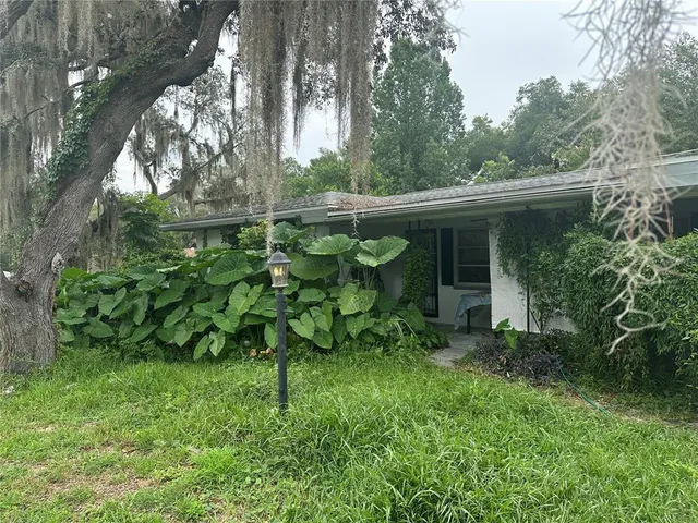 a backyard of a house with table and chairs and potted plants