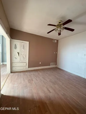 an empty room with windows and fan