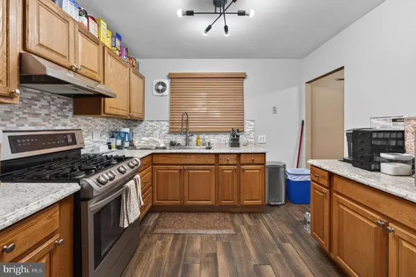 a kitchen with stainless steel appliances granite countertop wooden cabinets stove top oven and sink