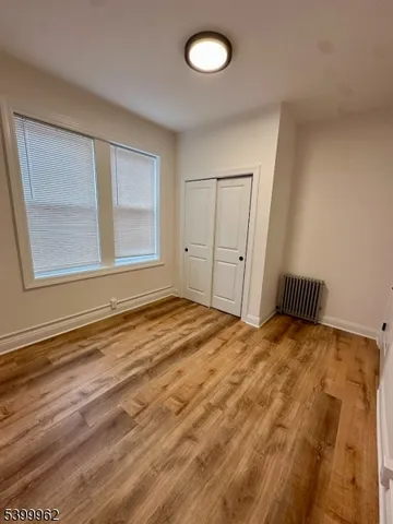 a view of empty room with window and wooden floor