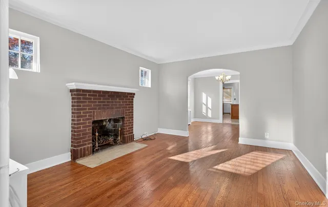 a view of an empty room with wooden floor and a fireplace