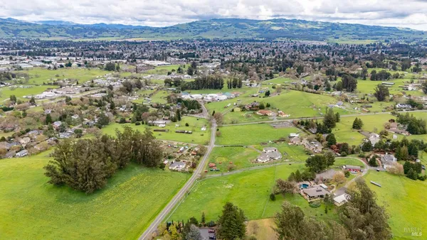 an aerial view of residential houses with outdoor space and trees