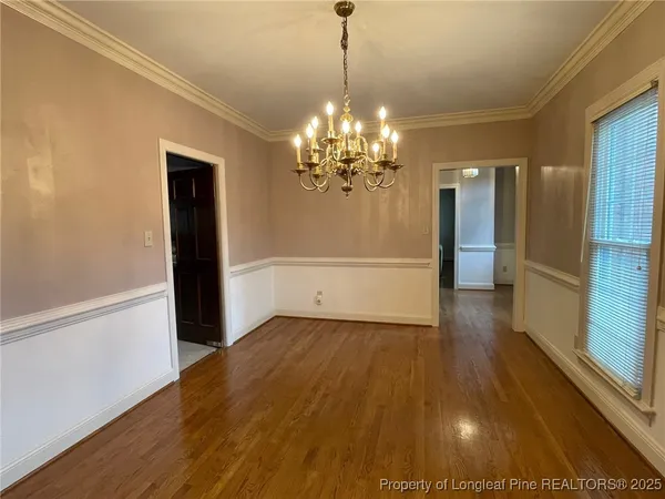 a view of a hallway with wooden floor and chandelier
