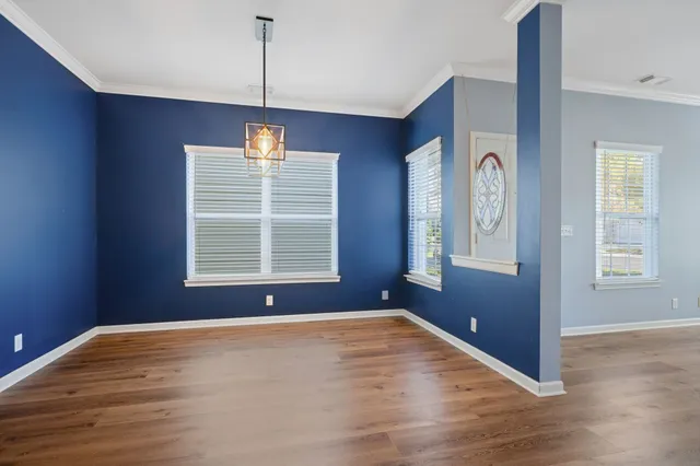 a view of an empty room with window and wooden floor