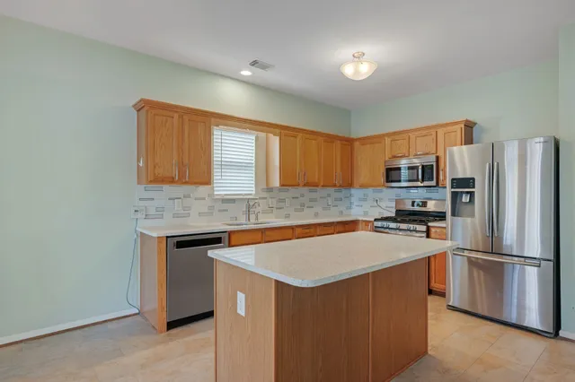 a kitchen with stainless steel appliances a refrigerator a sink a stove a microwave and island