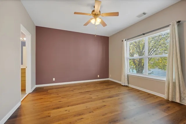 a view of an empty room with window and a chandelier fan