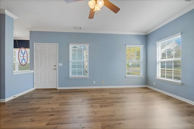 a view of an empty room with a window and wooden floor