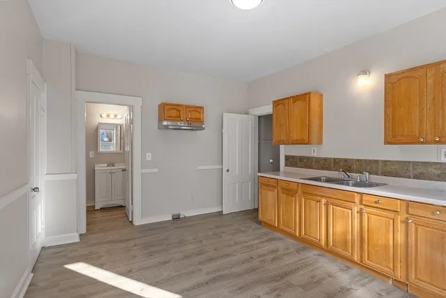 a view of a kitchen with stainless steel appliances wooden floor and chair