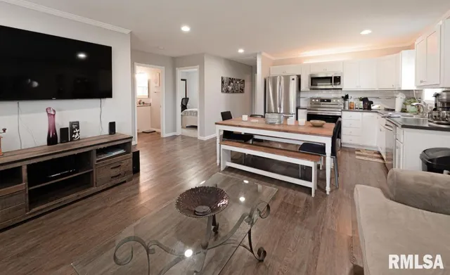a living room with stainless steel appliances furniture and a flat screen tv