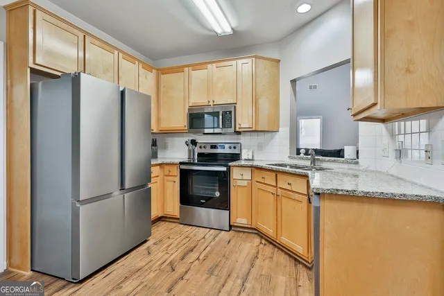 a kitchen with granite countertop stainless steel appliances a refrigerator a sink a stove a microwave and cabinets