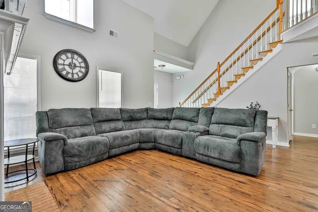 a living room with furniture a clock and a ceiling fan