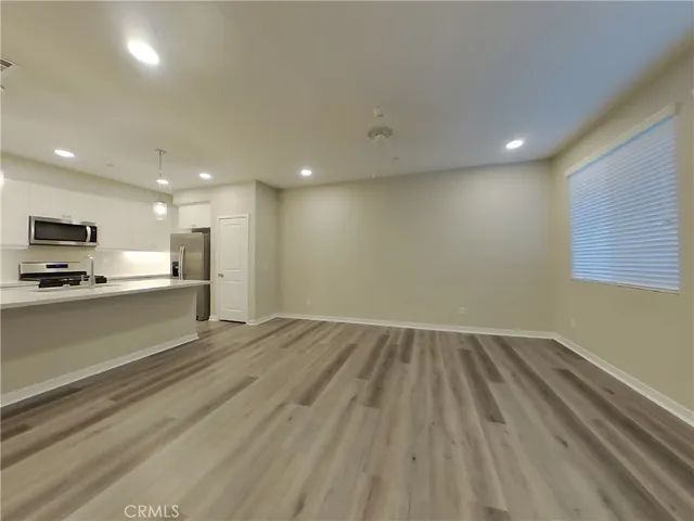 a view of kitchen and empty room with wooden floor