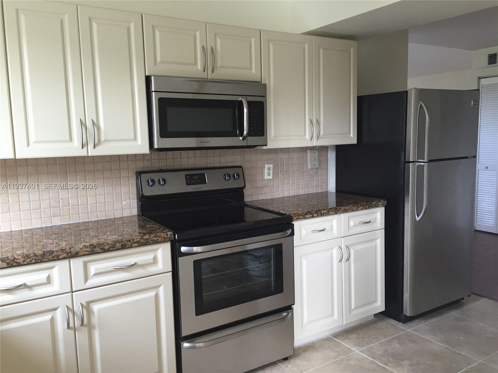 10441 Southwest 156th Court, Unit 421 Miami, FL 33196 - Photo 13 of 36 a kitchen with stainless steel appliances granite countertop white cabinets sink and a granite counter top