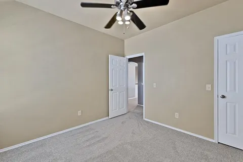 a view of an empty room and chandelier fan