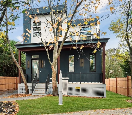 a view of a house with a small yard and a large tree