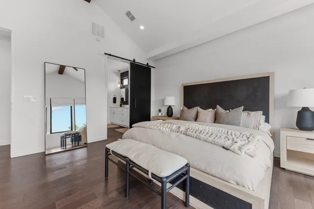 a spacious bedroom with a bed and wooden floor