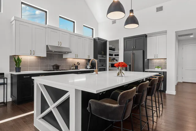 a kitchen with stainless steel appliances granite countertop a table chairs stove and refrigerator